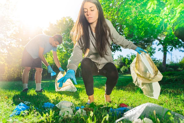 Coronavirus. Çift yeşil çimlerin üzerinde yatan koronavirüs salgını sırasında mavi lastik eldiven ve yüz maskesi alıyor. Çevre kirliliği. Çöp.. 