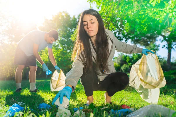Coronavirus. Çift yeşil çimlerin üzerinde yatan koronavirüs salgını sırasında mavi lastik eldiven ve yüz maskesi alıyor. Çevre kirliliği. Çöp.. 