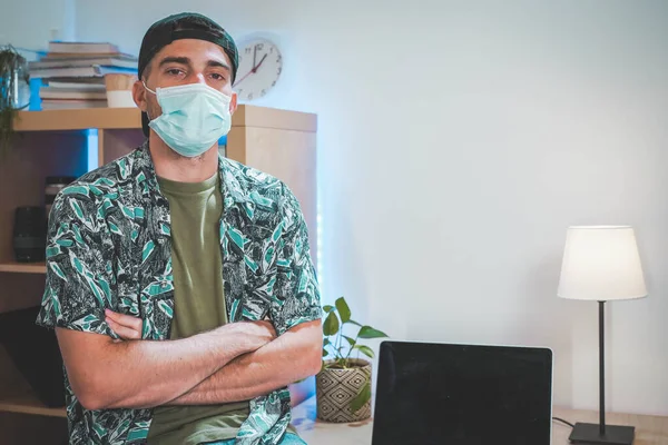 Portrait of a young man with face mask working from home. Amazing work space. Working in video and photo edit. Coronavirus.