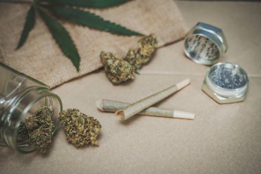 Önceden sarılmış CBD tıbbi marihuana ve ahşap arka planda kenevir yaprakları. Organik ve doğal kenevir bazlı kozmetik ve güzellik ürünleri. Tıbbi kenevir konsepti. Durgun hayat.