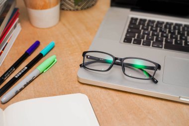 Bilgisayarlı güzel bir çalışma alanı. Küçük bir şirket çalışıyor ve iş yapıyor. Ev işi. Küçük ofis. Coronavirus. Gözlükler.