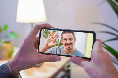 Bir iş adamının iş arkadaşlarıyla video konferans planı hakkında konuştuğu görüntüler. İş ekibi görüntülü görüşme için cep telefonunu kullanıyor. Evden çalışan bir grup zeki insan..