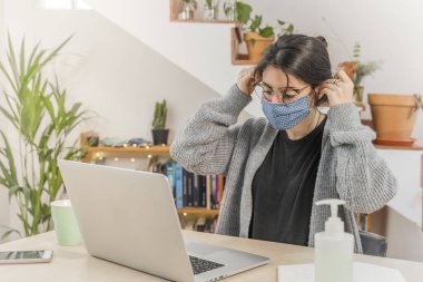 Coronavirus. Genç iş kadını evden izole edilmiş, koruyucu maske takıyor. Coronavirus yüzünden karantinada olan bir kadın işe gitmeden önce yüz maskesi takıyor. Karantina. 