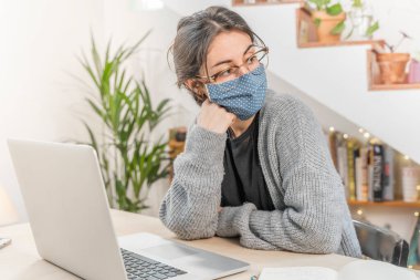 Coronavirus. Genç iş kadını evden izole edilmiş, koruyucu maske takıyor. Coronavirus yüzünden karantinada olan kadın yorgun ve bitkin. Evde kal. Karantinaya alın. Bunalımlı. 
