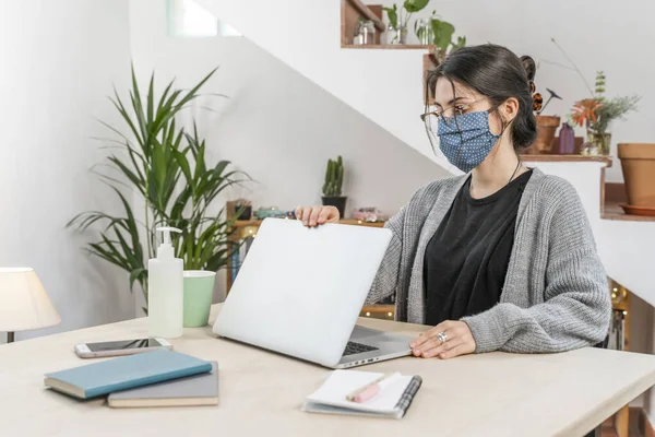 Coronavirus. Young business woman isolated working from home wearing protective mask. Woman in quarantine for coronavirus wearing home made mask. Working from home with sanitizer gel. Quarantine.