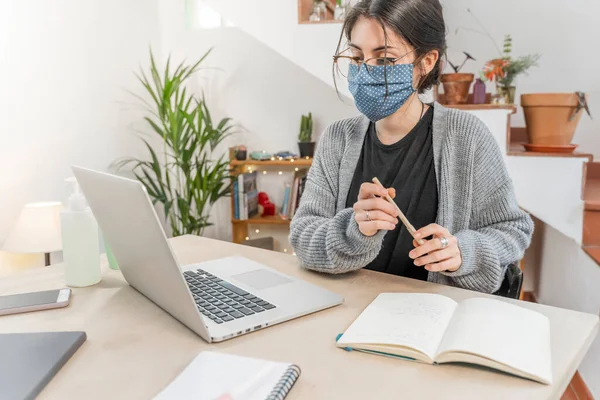 Coronavirus. Young business woman isolated working from home wearing protective mask. Woman in quarantine for coronavirus wearing home made mask. Working from home with sanitizer gel. Quarantine.