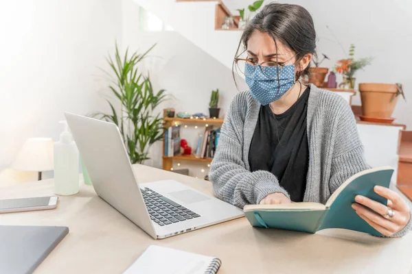 Coronavirus. Young business woman isolated working from home wearing protective mask. Woman in quarantine for coronavirus wearing home made mask. Working from home with sanitizer gel. Quarantine.