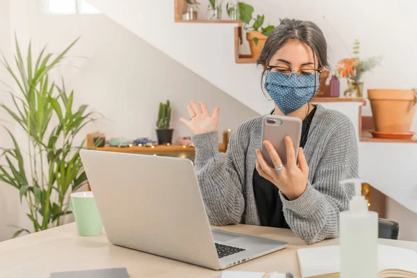 Coronavirus. Young business woman isolated working from home wearing protective mask. Woman in quarantine for coronavirus wearing home made mask. Working with mobile phone. Quarantine.