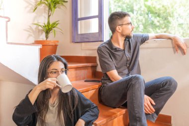 Coronavirus. Arkadaşları evde kahve yapıyor ve Coronavirus sırasında pencerenin yanında konuşuyorlar. Karantina konsepti. İşçiler. İzole edilmiş. Mola zamanı..