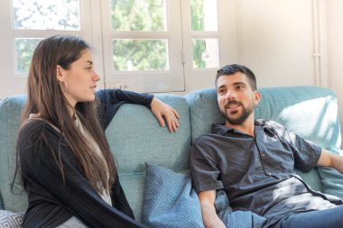 Coronavirus. Bir çift, Coronavirus sırasında evdeki karantinada kanepede oturuyor. Evdeki çift kanepede gülüp konuşuyor. - Eve. Evde kal.. 