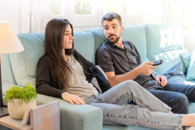 Coronavirus. Koronavirüs sırasında evde karantinada televizyon izleyen bir çift. Bu arada evdeki çift kanepede gülüp sohbet ediyor ve televizyon seyrediyor. - Eve. Evde kal.. 