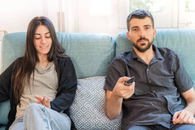 Coronavirus. Koronavirüs sırasında evde karantinada televizyon izleyen bir çift. Bu arada evdeki çift kanepede gülüp sohbet ediyor ve televizyon seyrediyor. - Eve. Evde kal.. 