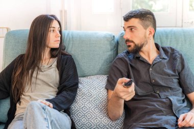 Coronavirus. Koronavirüs sırasında evde karantinada televizyon izleyen bir çift. Bu arada evdeki çift kanepede gülüp sohbet ediyor ve televizyon seyrediyor. - Eve. Evde kal..