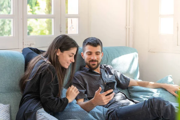 Coronavirus. Bir çift, Coronavirus sırasında evdeki karantinada kanepede oturuyor. Evdeki çift kanepede oturuyor, cep telefonuna bakıyor ve konuşuyor. - Eve. Evde kal.. 