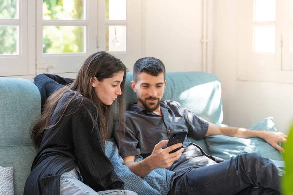 Coronavirus. Bir çift, Coronavirus sırasında evdeki karantinada kanepede oturuyor. Evdeki çift kanepede oturuyor, cep telefonuna bakıyor ve konuşuyor. - Eve. Evde kal.. 