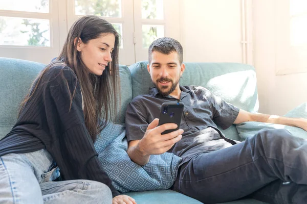 Coronavirus. Bir çift, Coronavirus sırasında evdeki karantinada kanepede oturuyor. Evdeki çift kanepede oturuyor, cep telefonuna bakıyor ve konuşuyor. - Eve. Evde kal.. 