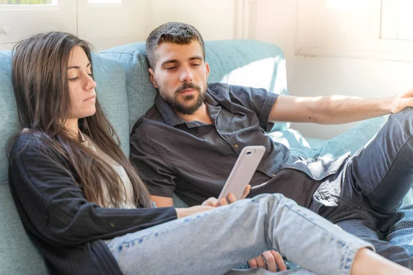 Coronavirus. Bir çift, Coronavirus sırasında evdeki karantinada kanepede oturuyor. Evdeki çift kanepede oturuyor, cep telefonuna bakıyor ve konuşuyor. - Eve. Evde kal.. 