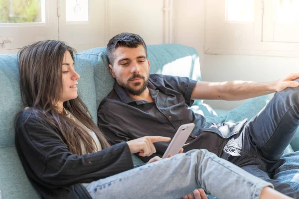 Coronavirus. Bir çift, Coronavirus sırasında evdeki karantinada kanepede oturuyor. Evdeki çift kanepede kitap izliyor ve konuşuyor. - Eve. Evde kal.. 