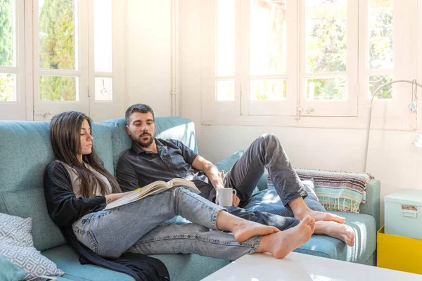 Coronavirus. Bir çift, Coronavirus sırasında evdeki karantinada kanepede oturuyor. Evdeki çift kanepede kitap izliyor ve konuşuyor. - Eve. Evde kal.. 