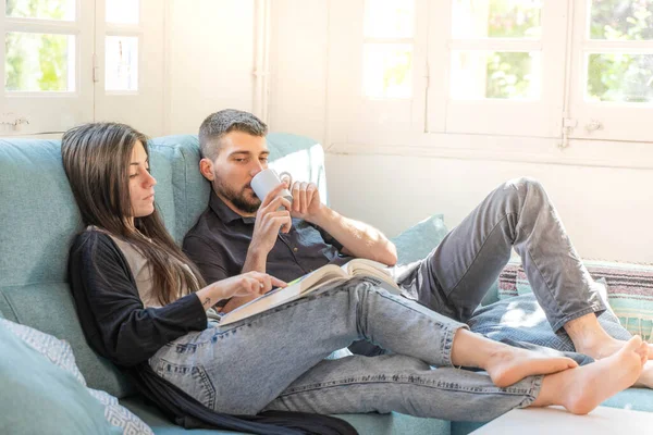 Coronavirus. Bir çift, Coronavirus sırasında evdeki karantinada kanepede oturuyor. Evdeki çift kanepede kitap izliyor ve konuşuyor. - Eve. Evde kal.. 