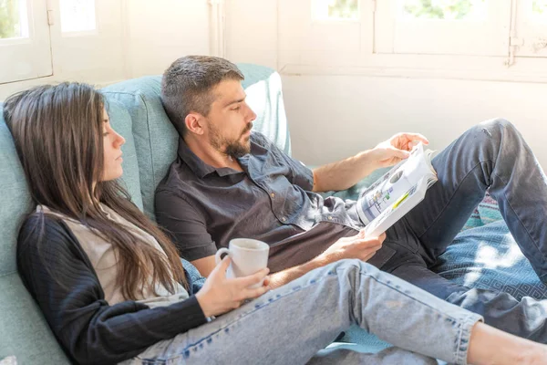 Coronavirus. Bir çift, Coronavirus sırasında evdeki karantinada kanepede oturuyor. Evdeki çift kanepede kitap izliyor ve konuşuyor. - Eve. Evde kal.. 