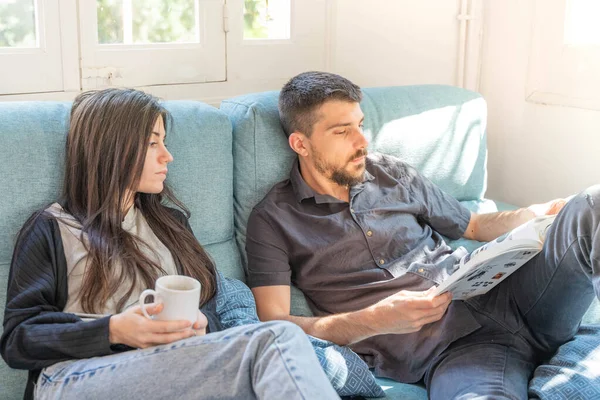 Coronavirus. Bir çift, Coronavirus sırasında evdeki karantinada kanepede oturuyor. Evdeki çift kanepede kitap izliyor ve konuşuyor. - Eve. Evde kal.. 