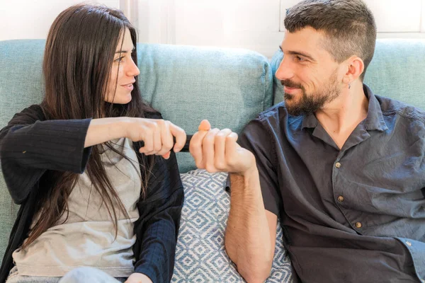 Coronavirus. A couple sitting on the couch watching tv on a quarantine at home, during  coronavirus. Couple at home on the couch laughing and arguing for the television command. Home. Stay home.