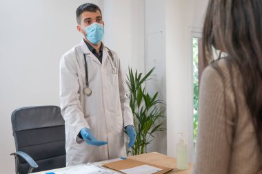 Coronavirus. Doktor sağlıksız kadını ziyaret ediyor. Doktor hastaya danışıyor. Önleme için yüz maskesi ve lastik eldiven kullanıyorlar. Hasta bakımı. Teşhisler. Coronavirus belirtileri