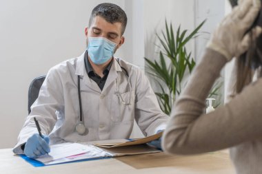 Coronavirus. Doktor sağlıksız kadını ziyaret ediyor. Doktor hastaya danışıyor. Önleme için yüz maskesi ve lastik eldiven kullanıyorlar. Hasta bakımı. Teşhisler. Coronavirus belirtileri