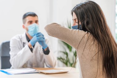 Coronavirus. Doktor sağlıksız kadını ziyaret ediyor. Doktor hastaya danışıyor. Önleme için yüz maskesi ve lastik eldiven kullanıyorlar. Hasta bakımı. Teşhisler. Coronavirus belirtileri