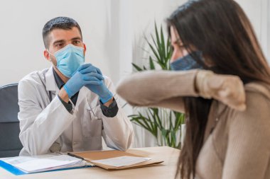 Coronavirus. Doktor sağlıksız kadını ziyaret ediyor. Doktor hastaya danışıyor. Önleme için yüz maskesi ve lastik eldiven kullanıyorlar. Hasta bakımı. Teşhisler. Coronavirus belirtileri