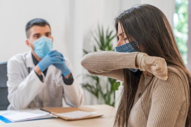 Coronavirus. Doktor sağlıksız kadını ziyaret ediyor. Doktor hastaya danışıyor. Önleme için yüz maskesi ve lastik eldiven kullanıyorlar. Hasta bakımı. Teşhisler. Coronavirus belirtileri