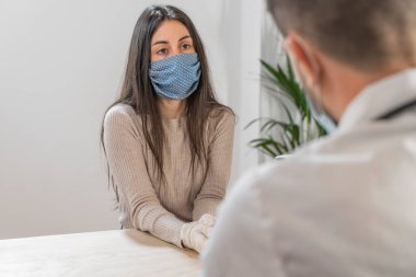 Coronavirus. Doktor sağlıksız kadını ziyaret ediyor. Doktor hastaya danışıyor. Önleme için yüz maskesi ve lastik eldiven kullanıyorlar. Hasta bakımı. Teşhisler. Coronavirus belirtileri. Temizleyici jel..