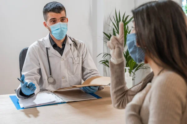 Coronavirus. Doktor sağlıksız kadını ziyaret ediyor. Doktor hastaya danışıyor. Önleme için yüz maskesi ve lastik eldiven kullanıyorlar. Hasta bakımı. Teşhisler. Coronavirus belirtileri