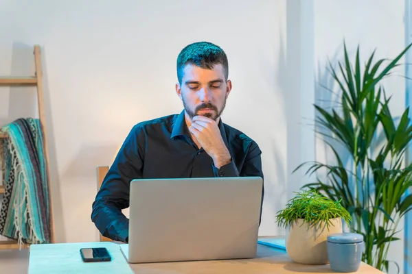 Evde bilgisayarla çalışan bir iş adamı. Küçük bir şirket çalışıyor ve iş yapıyor. Karantina sırasında evde çalışmak. Küçük ofis. Coronavirus. Temizleyici jel ve yüz maskesi..