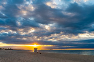 Mavi suları olan kumlu bir sahilde güzel bir gün batımı. Akdeniz 'in rahatlatıcı yaz manzarası. Temiz ve berrak okyanus. Gezegen kavramını sakla. Tatil ekran koruyucusu.