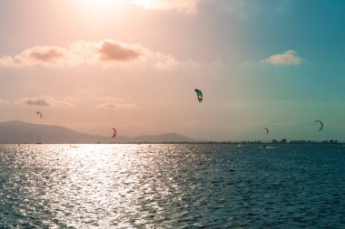 Güzel bir gün batımında, kumlu bir sahilde, mavi sularda uçurtma sörfü. Akdeniz 'in rahatlatıcı yaz manzarası. Temiz ve berrak okyanus. Gezegen kavramını sakla. Tatil ekran koruyucusu.
