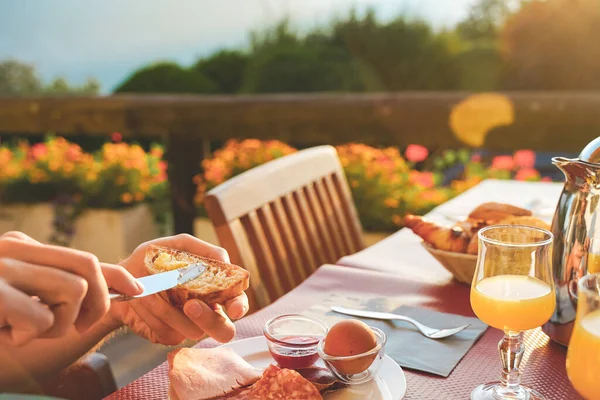 Amazing breakfast table in nature during a sunny day with beautiful  view. Healthy breakfast with toast, fruit slices, fresh juice, yoghurt, nuts and maple sirup. Homemade.