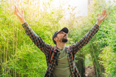 Genç, mutlu bir gezgin, güzel bir ormanda sırt çantasıyla yürüyüş yapıyor. Seyahat ve macera konsepti. Kırsalda yürüyüş yapan gençler. 