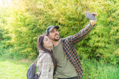 Genç ve mutlu gezginler gece vakti güzel bir ormanda sırt çantasıyla yürüyüşe çıkıyorlar. Aile seyahati ve macera konsepti. Kırsalda yürüyüş yapan gençler. Cep telefonu kullanıyorlar.. 