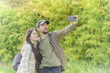 Genç ve mutlu gezginler gece vakti güzel bir ormanda sırt çantasıyla yürüyüşe çıkıyorlar. Aile seyahati ve macera konsepti. Kırsalda yürüyüş yapan gençler. Cep telefonu kullanıyorlar.. 