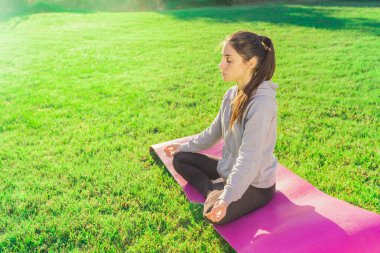 Sabahları bahçesinde yoga yapan genç bir kadın. Nilüfer pozisyonunda güneş ışığı, namaste, spor kıyafetleri giymiş.. 