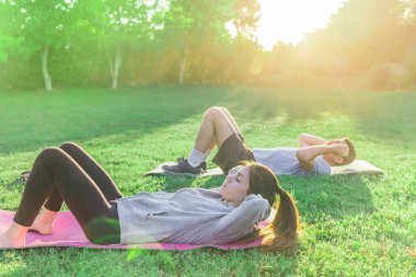 Genç bir çift sabah bahçelerinde güneş ışığında egzersiz yapıyor. Reklam yapıyor ve spor kıyafetleri giyiyor.. 