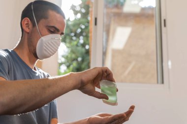 Coronavirus. Karantinadaki adam koronavirüs için koruyucu maske takıyor. Evden çalışıyorum. Ellerini dezenfektan jeliyle temizliyor. Koronavirüsten koru ve genellikle ellerini temizle..