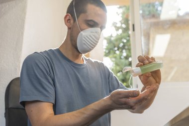 Coronavirus. Karantinadaki adam koronavirüs için koruyucu maske takıyor. Evden çalışıyorum. Ellerini dezenfektan jeliyle temizliyor. Koronavirüsten koru ve genellikle ellerini temizle..