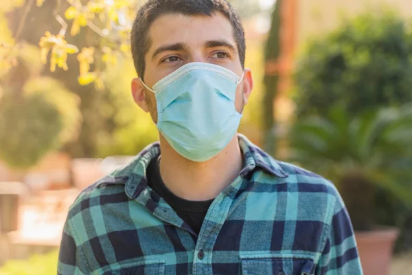 Young man with face mask portrait in the sunshine nature. Coronavirus concept. No more quarantine. Breathe deep.