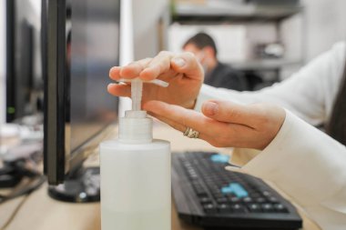 Coronavirus. İş adamları koruyucu maske takıp dezenfektan jel kullanıyor. Coronavirus için karantinada küçük bir şirket dezenfektan jeliyle çalışıyor. Küçük şirket konsepti.