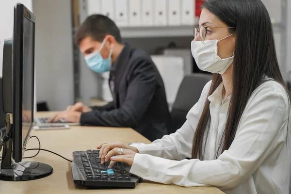 Business workers working in small company with computers and face mask. Small company working and doing business. Small company and team work concept. Little office. Home working during quarantine. Coronavirus.