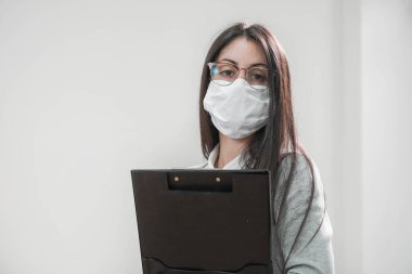 Coronavirus. Beyaz bir arka planda koruyucu maske takan kendine güvenen bir iş kadını portresi. Yüzü maskeli bir iş kadını tecritten sonra işe geri dönüyor. Küçük şirket konsepti.