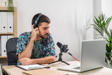 Radyoda radyo sunucusu olarak çalışan adam mikrofonun önünde oturuyor. Genç radyo sunucusu yüz maskeli bir radyo için canlı yayın yapıyor. Evde çalışıyorum. Coronavirüs.